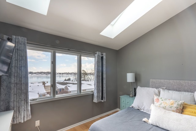 bedroom featuring hardwood / wood-style flooring, lofted ceiling with skylight, and a water view