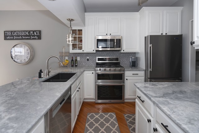 kitchen featuring appliances with stainless steel finishes, pendant lighting, white cabinetry, sink, and dark hardwood / wood-style flooring