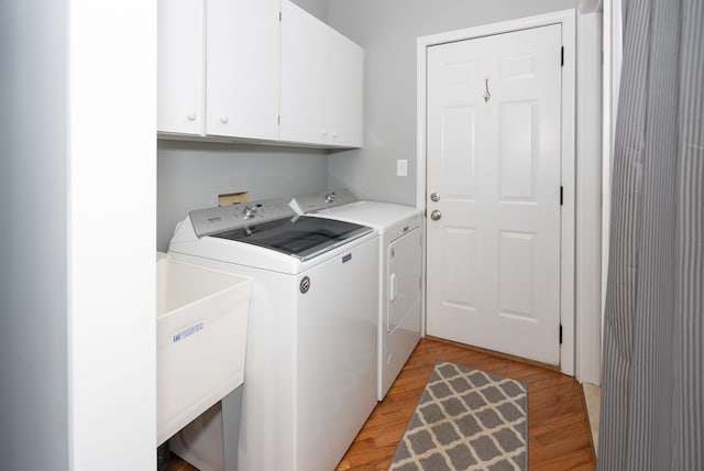 laundry room featuring cabinets, sink, washer and clothes dryer, and light hardwood / wood-style floors