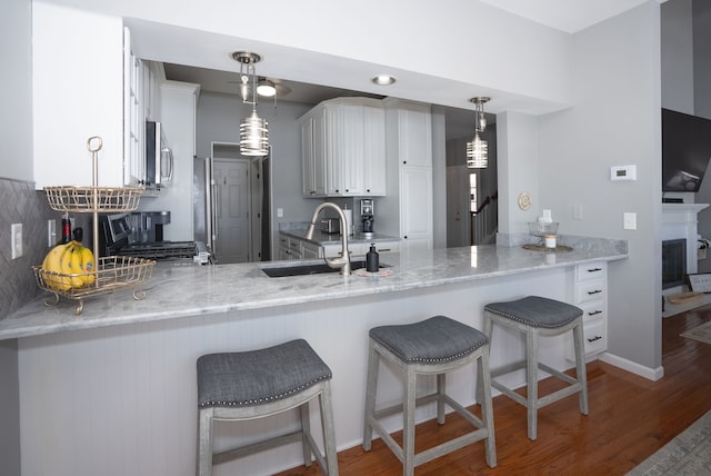 kitchen with range, decorative light fixtures, sink, and white cabinets