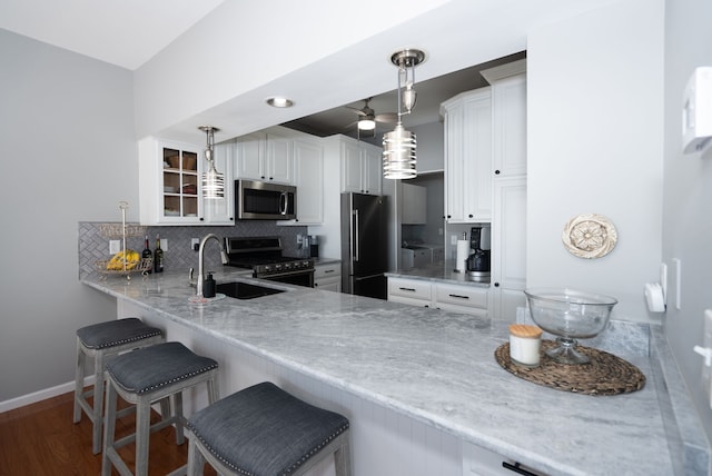 kitchen with white cabinetry, appliances with stainless steel finishes, a kitchen bar, and hanging light fixtures