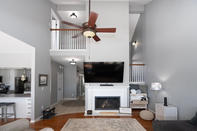 living room featuring ceiling fan, wood-type flooring, and a towering ceiling