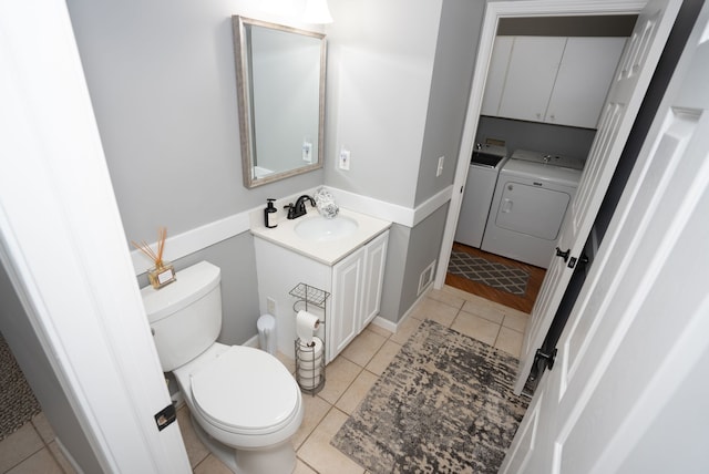 bathroom featuring tile patterned flooring, vanity, washer and dryer, and toilet