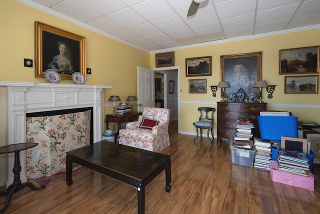 living room with hardwood / wood-style floors, a fireplace, ornamental molding, and ceiling fan