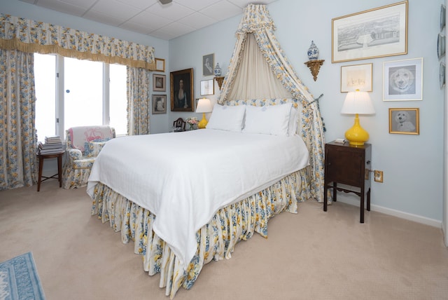 bedroom featuring a paneled ceiling and light carpet