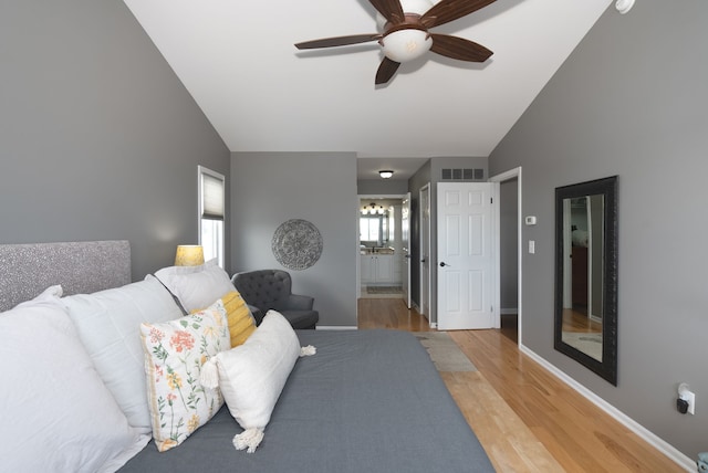 bedroom with ceiling fan, connected bathroom, high vaulted ceiling, and light wood-type flooring