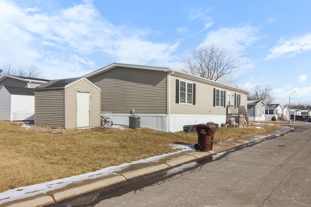 view of property exterior featuring a shed, a yard, and central air condition unit