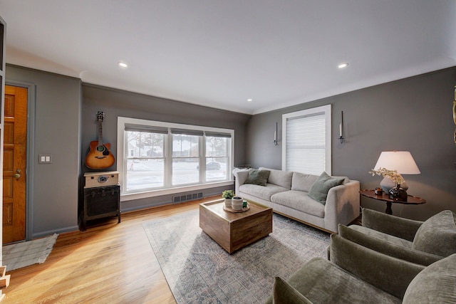 living room featuring crown molding and light hardwood / wood-style flooring