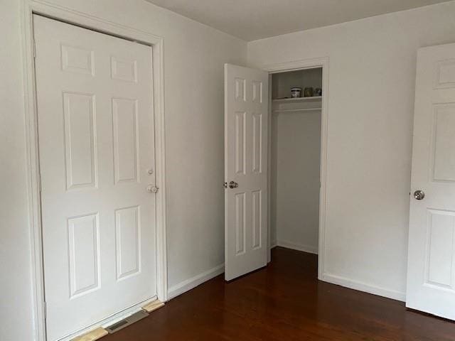 unfurnished bedroom featuring dark hardwood / wood-style flooring and a closet