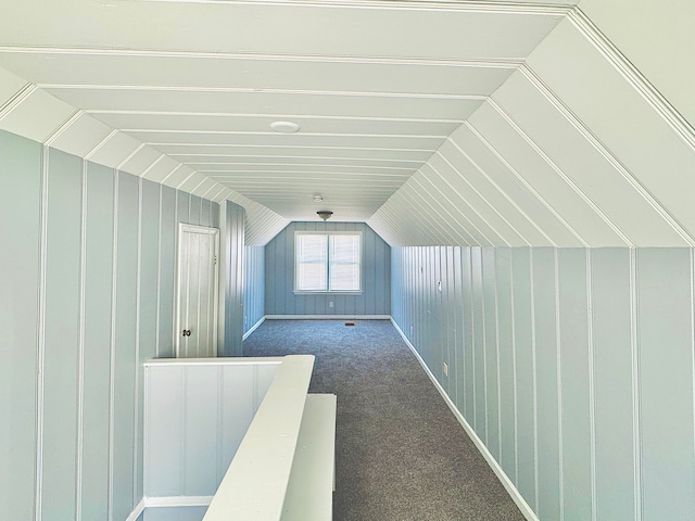 additional living space with lofted ceiling, wooden walls, and dark carpet