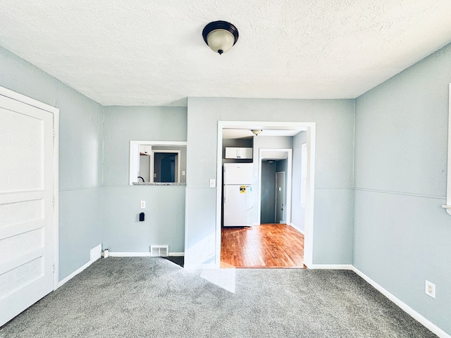 carpeted spare room featuring a textured ceiling