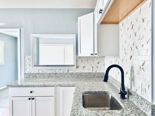 kitchen featuring tasteful backsplash, white cabinetry, and sink