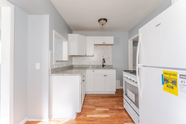 kitchen with white appliances, white cabinetry, light stone counters, tasteful backsplash, and light hardwood / wood-style floors