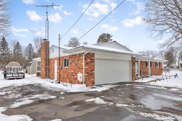 11870 Woodland Dr, Lennon, MI 48449 - snow covered property with brick siding, a chimney, a garage, and asphalt driveway