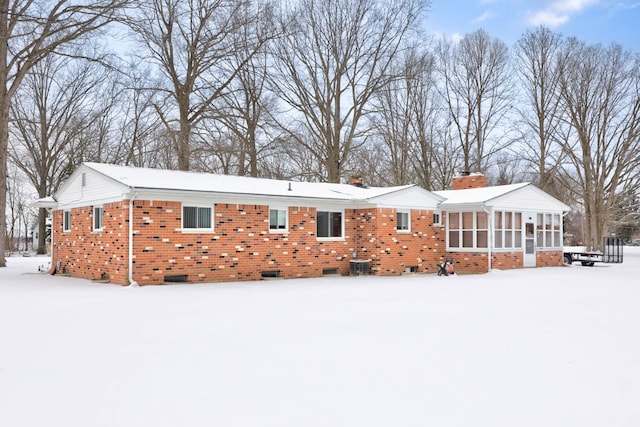 11870 Woodland Dr, Lennon, MI 48449 - snow covered rear of property featuring a sunroom, brick siding, a chimney, and crawl space