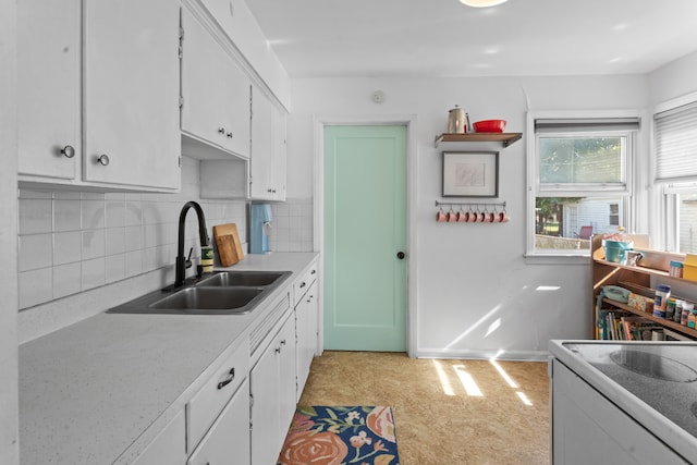 kitchen with tasteful backsplash, light countertops, white cabinets, a sink, and baseboards