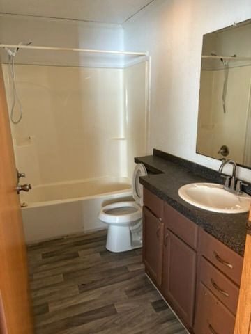 full bathroom with hardwood / wood-style flooring, vanity, tub / shower combination, and toilet