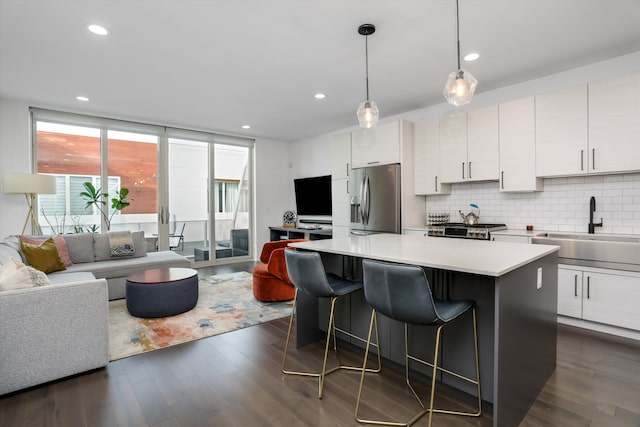 kitchen featuring sink, stainless steel fridge, backsplash, white cabinets, and a kitchen island