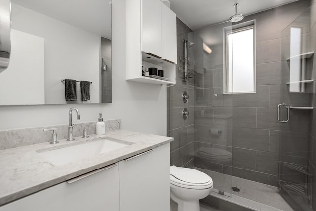 bathroom featuring vanity, a shower with shower door, and toilet