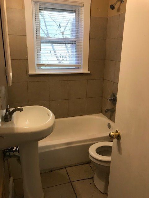 bathroom with tiled shower / bath, tile patterned floors, and toilet