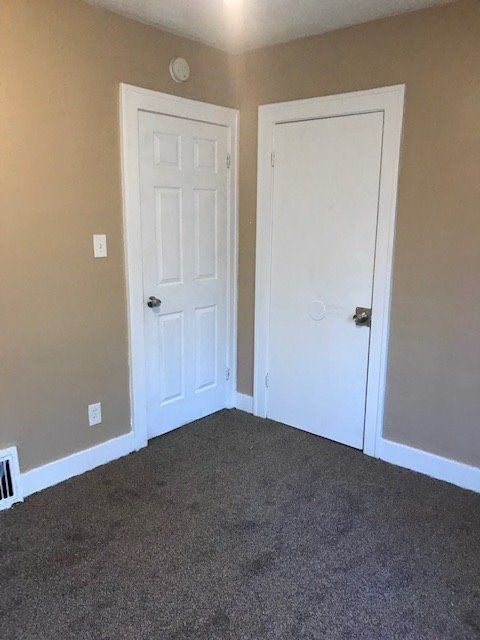 unfurnished bedroom with dark colored carpet