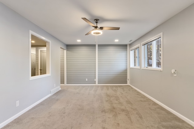 empty room with ceiling fan and light carpet