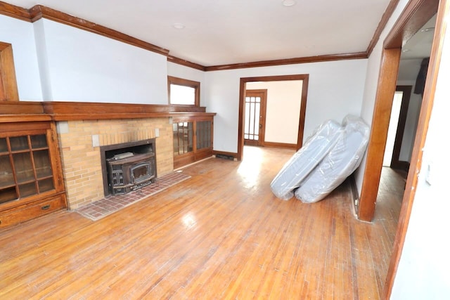 living room featuring ornamental molding, a wood stove, baseboards, and hardwood / wood-style floors