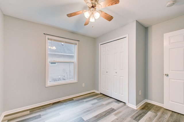 unfurnished bedroom with ceiling fan, a closet, and light wood-type flooring