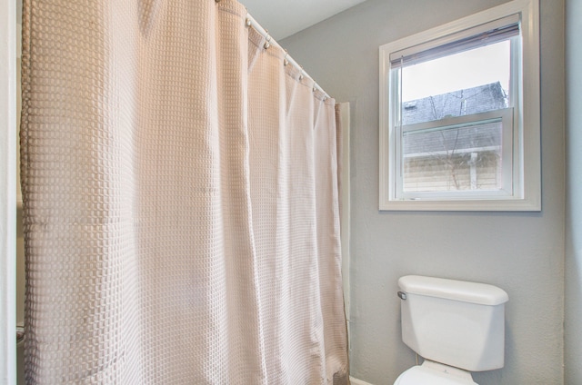 bathroom with toilet and a shower with shower curtain