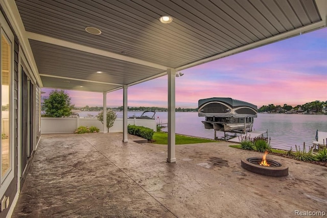 view of patio with an outdoor fire pit, a dock, a water view, and boat lift