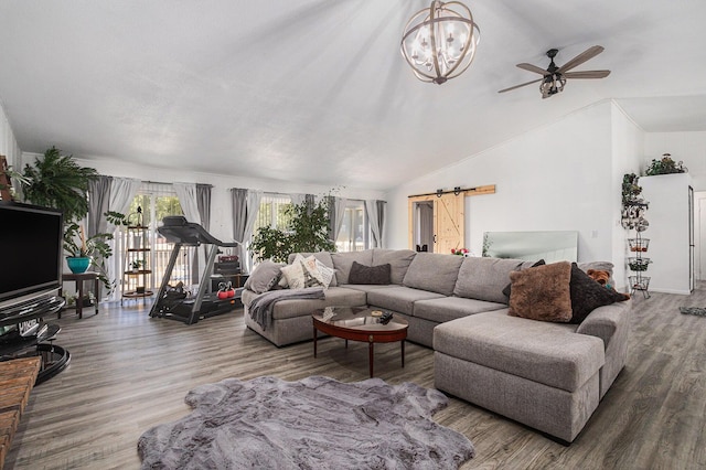 living room with lofted ceiling, hardwood / wood-style flooring, a barn door, and ceiling fan