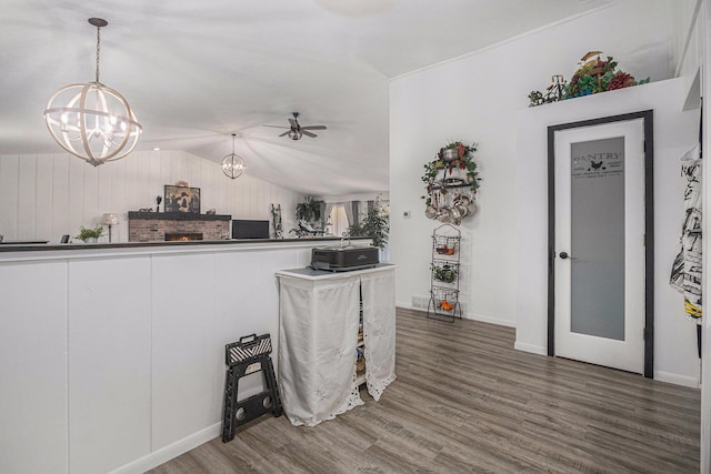 kitchen with hanging light fixtures, vaulted ceiling, dark hardwood / wood-style floors, and ceiling fan with notable chandelier