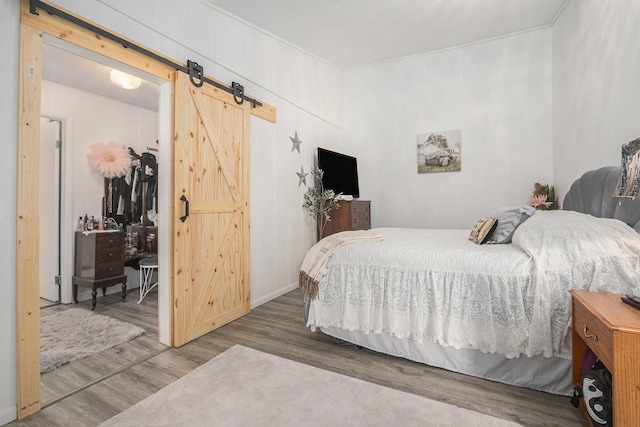 bedroom with hardwood / wood-style flooring and a barn door