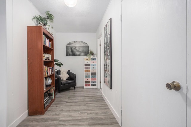 hallway with a textured ceiling and light wood-type flooring