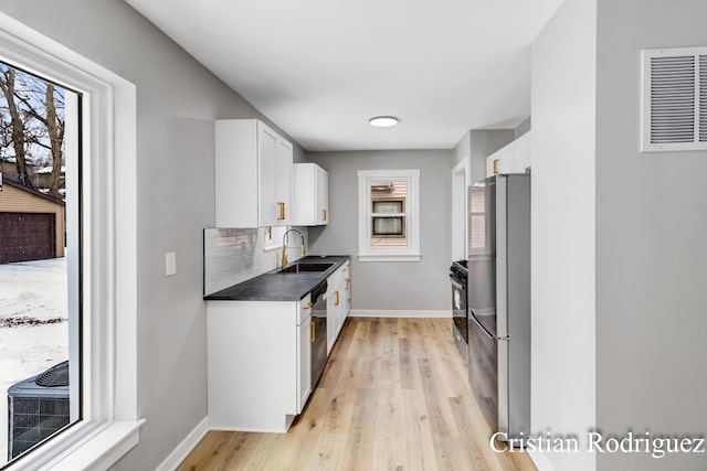 kitchen with white cabinetry, sink, stainless steel appliances, and light wood-type flooring