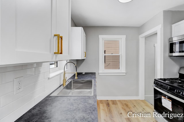 kitchen featuring white cabinetry, sink, light hardwood / wood-style floors, and black gas stove