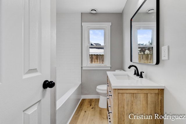 full bathroom featuring vanity, tiled shower / bath, wood-type flooring, and toilet