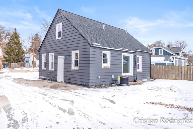 snow covered back of property featuring central AC