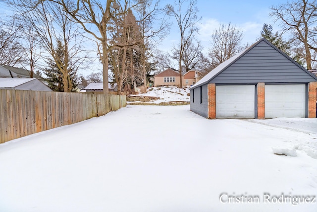 snowy yard with a garage and an outdoor structure