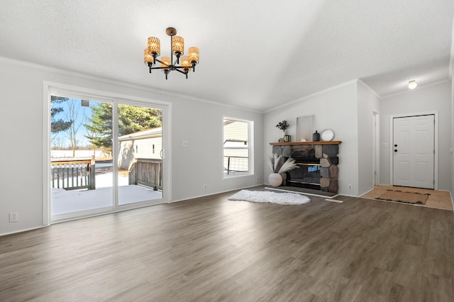 unfurnished living room featuring crown molding, hardwood / wood-style floors, a notable chandelier, a textured ceiling, and a stone fireplace