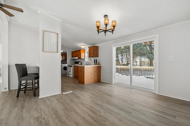 kitchen featuring a breakfast bar area, crown molding, light wood-type flooring, kitchen peninsula, and white range