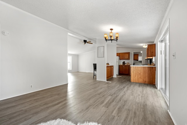 unfurnished living room featuring lofted ceiling, hardwood / wood-style floors, ceiling fan with notable chandelier, and a textured ceiling