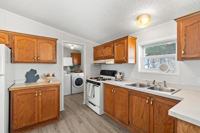 kitchen featuring lofted ceiling, sink, crown molding, separate washer and dryer, and white appliances