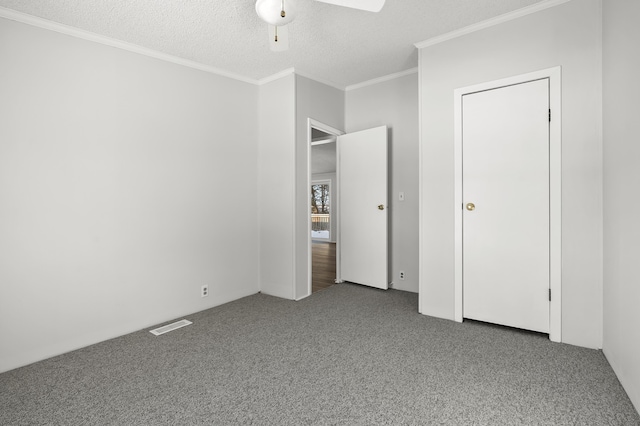 unfurnished bedroom featuring ceiling fan, carpet floors, ornamental molding, and a textured ceiling