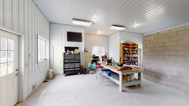 interior space with concrete block wall, metal wall, and a workshop area