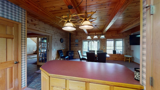 dining room with a wood stove, wood ceiling, wooden walls, and beam ceiling