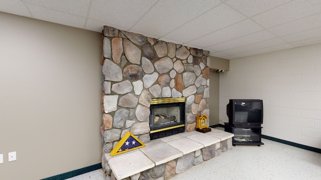 room details with a fireplace, baseboards, and a drop ceiling