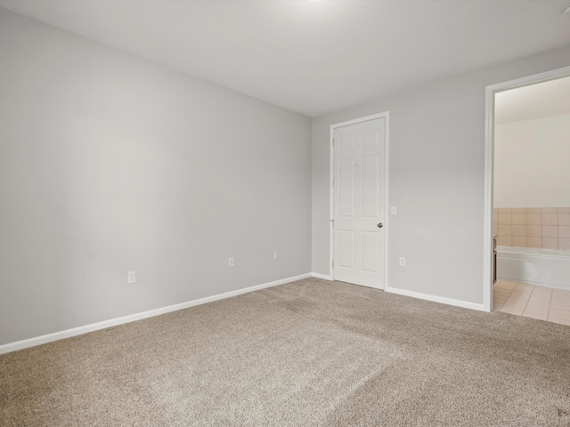 unfurnished bedroom featuring ensuite bathroom and light colored carpet