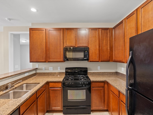 kitchen featuring sink, black appliances, and light stone countertops