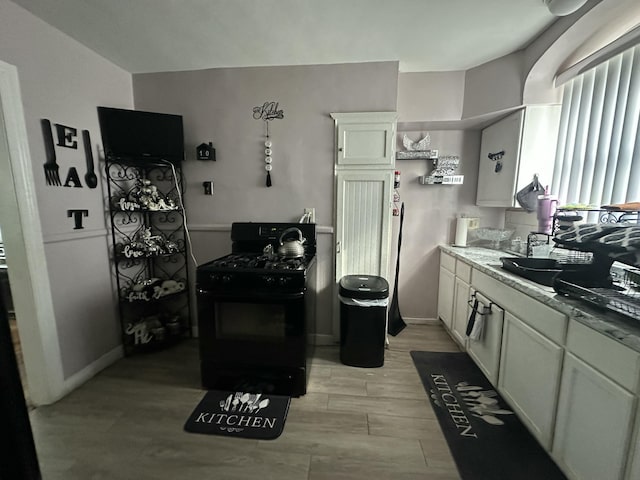 kitchen with white cabinetry, black range with gas stovetop, and light hardwood / wood-style floors